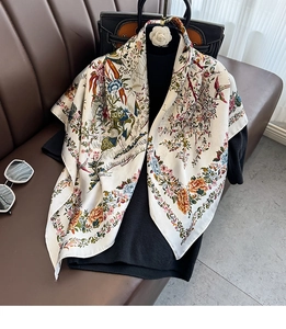 Dettaglio di sciarpa in seta con eleganti motivi floreali e uccelli su tessuto crema