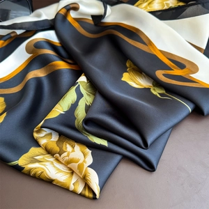 Vintage floral silk scarf with golden flower patterns and smooth satin texture on brown leather