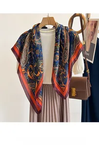 Detail of silk-like navy scarf with paisley pattern draped on a white knit sweater