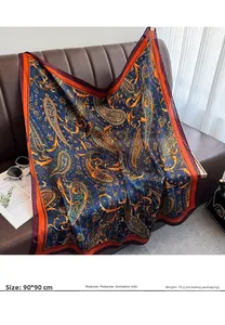 Detail of soft 90x90cm paisley silk scarf draped over leather sofa with fashion accessories