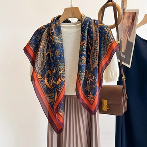 Elegant paisley patterned silk-like scarf draped over a white top for office wear