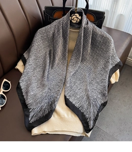 Detail of luxury silk scarf with black and white texture draped over casual knitwear