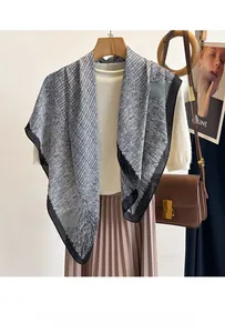 Elegant silk scarf with black and white woven pattern and solid black border on mannequin