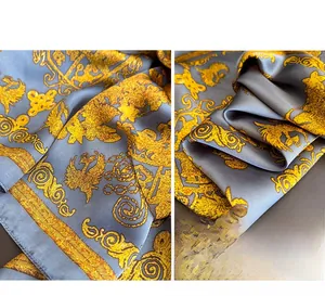 Detailed close-up of Baroque pattern silk scarf featuring golden scrolls on grey satin
