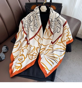 Detailed view of luxury silk scarf floral print and vibrant orange hemline drape