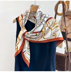 Close-up of printed silk scarf with abstract floral patterns and orange contrast borders