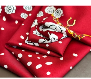Macro shot of red twill silk scarf with floral rose patterns and gold chain details