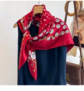 Detail view of red silk scarf featuring white camellias, polka dots, and golden chain prints