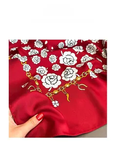 Detail of red twill silk scarf showing white rose, golden chains, and horseshoe prints