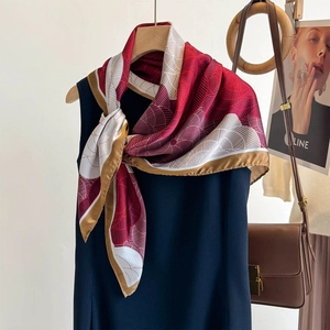 Red fashion square scarf with leaf patterns tied on a sleeveless dress on a wooden hanger