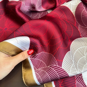 Silk-like fashion scarf with geometric floral print and silky drape held by hand