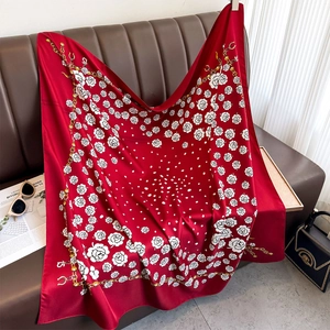 Elegant 90cm red silk scarf with rose and gold chain print on a brown leather sofa