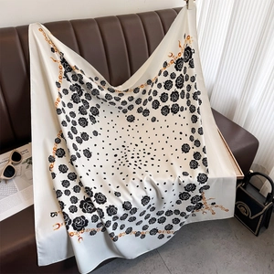 Detail of elegant black and white silk scarf with gold chain and camellia flower patterns