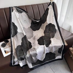 Detailed view of large black and white floral print square scarf draped over a leather sofa