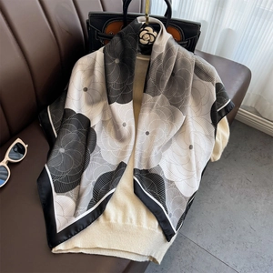 Elegant floral print silk scarf in black and white draped over a beige sweater