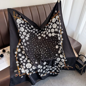 Close-up of silk scarf with white camellia and gold chain pattern on leather couch