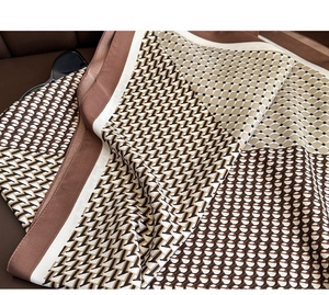 Détail d'un foulard en satin aux motifs géométriques marron sur une surface en cuir
