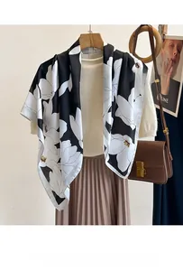 Détail d'un foulard en satin à fleurs porté avec un tricot beige et une jupe plissée brune