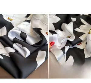 Détails du motif de lys noir et blanc sur le tissu lisse d'un foulard en soie satinée