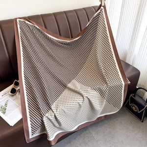 Élégant foulard en soie à carreaux géométriques drapé sur un canapé en cuir de luxe