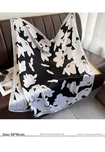 Détail d'un foulard en soie de 90 cm avec imprimé floral blanc sur un canapé en cuir