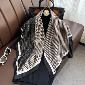 Élégant foulard en soie noir et blanc avec motifs pied-de-poule et géométriques sur sofa