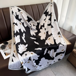 Élégant foulard en satin de soie avec imprimé magnolia drapé sur un canapé en cuir
