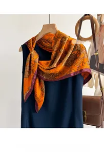 Détail d'un foulard en soie à motifs paisley orange et bordures en satin violet