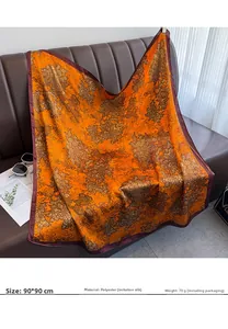 Détail d'un foulard 90x90cm orange en soie synthétique avec motifs floraux dorés