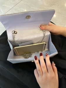 Detail of silver sequin evening bag interior showing purple lining and phone storage