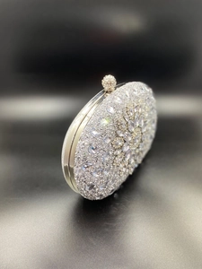 Close-up of silver shell clutch with full rhinestones and sparkling crystal ball clasp