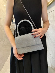 Sparkling silver evening clutch featuring a metal handle and elegant chain shoulder strap