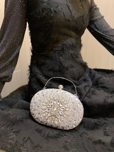 Detail view of silver shell clutch with radiant crystal floral patterns and rhinestones