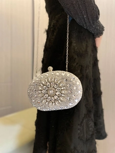 Side view of silver shell clutch bag with rhinestone flowers and a chain strap