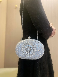Detail of silver shell-shaped evening bag featuring radial sunflower rhinestone patterns