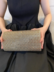 Luxury gold crystal evening clutch bag with geometric diamond pattern held by model