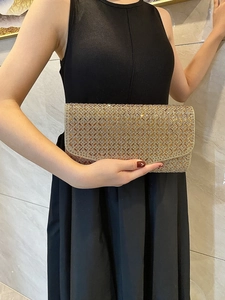 Champagne gold evening clutch bag with quilted crystal pattern held by a model
