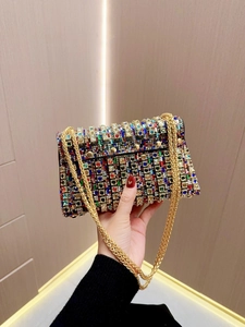 Detail of colorful rhinestones on evening bag with gold chain strap held by hand