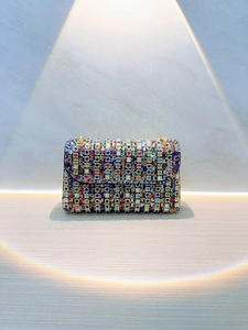 Detail of colorful rhinestone evening clutch with gold chain on marble background