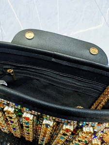 Detail of evening bag showing golden magnetic clasps, zipper pocket and colorful rhinestones