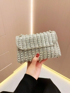 Close-up of sparkling silver rhinestone evening bag with chain strap held by hand