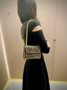 Fashionable rainbow rhinestone evening bag with gold chain strap worn by a model
