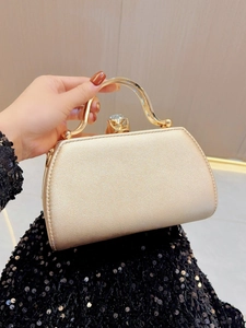 Detail of golden evening clutch bag featuring pearlescent finish and large gemstone clasp