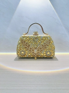 Macro detail of golden evening bag with crystal butterfly and floral gemstone pattern