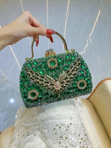 Detailed macro view of the emerald crystal clutch bag featuring a golden butterfly clasp