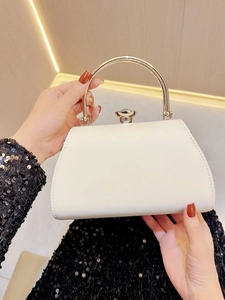 Detail of white evening bag featuring elegant metal handle and gemstone-shaped clasp