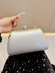 Detail of silver evening clutch bag featuring a gold handle and a large crystal clasp