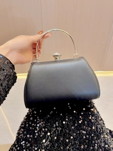 Detail of black evening handbag with gold semi-circle metal handle and crystal clasp