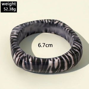 Macro shot of irregular black and white resin bangle showing weight 52.38g and 6.7cm diameter