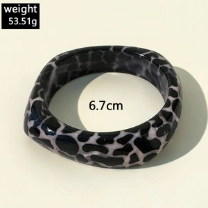Detail view of chunky resin bangle with black and white animal print pattern and 6.7cm diameter